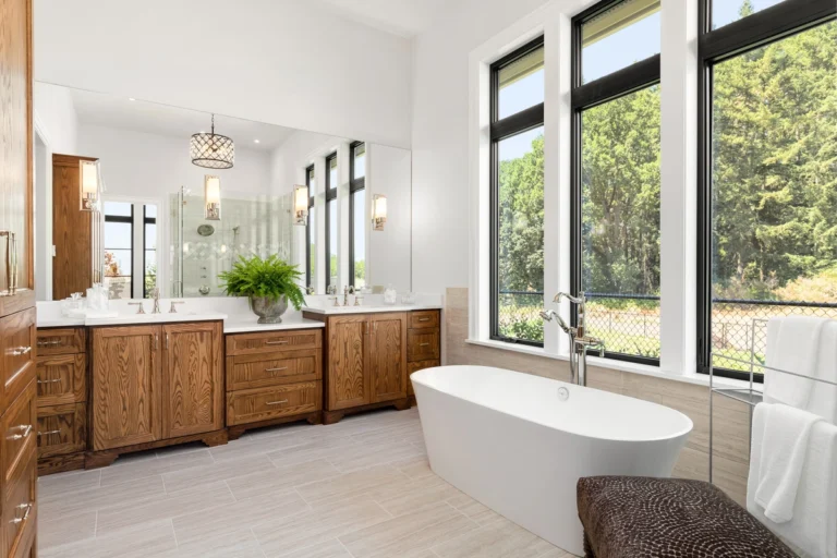 springtime bathroom renovation in Northwest Indiana; white standalone tub and elegant wood vanity with big window