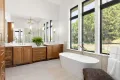 springtime bathroom renovation in Northwest Indiana; white standalone tub and elegant wood vanity with big window