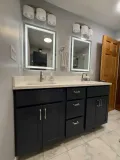 Remodeled upstairs bathroom in Lakes of the Four Seasons with a scalloped gray walk-in shower, custom glass door, double vanity, and Turkish White flooring.