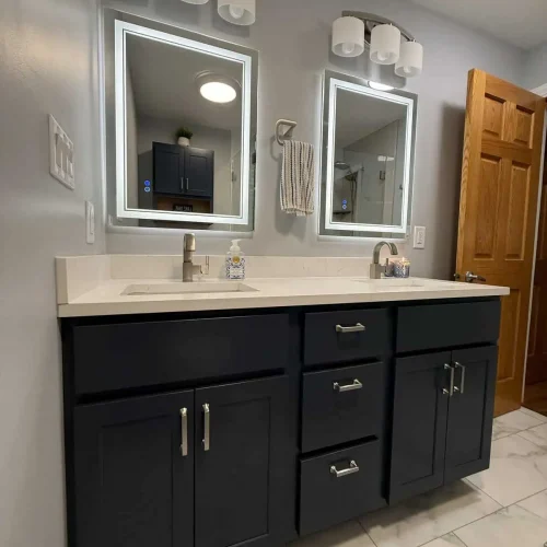 Remodeled upstairs bathroom in Lakes of the Four Seasons with a scalloped gray walk-in shower, custom glass door, double vanity, and Turkish White flooring.